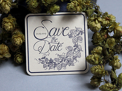 Eine Save the Date Karte auf einem Biedeckel gedruckt. Mit Hopfenranken dekoriert. 
